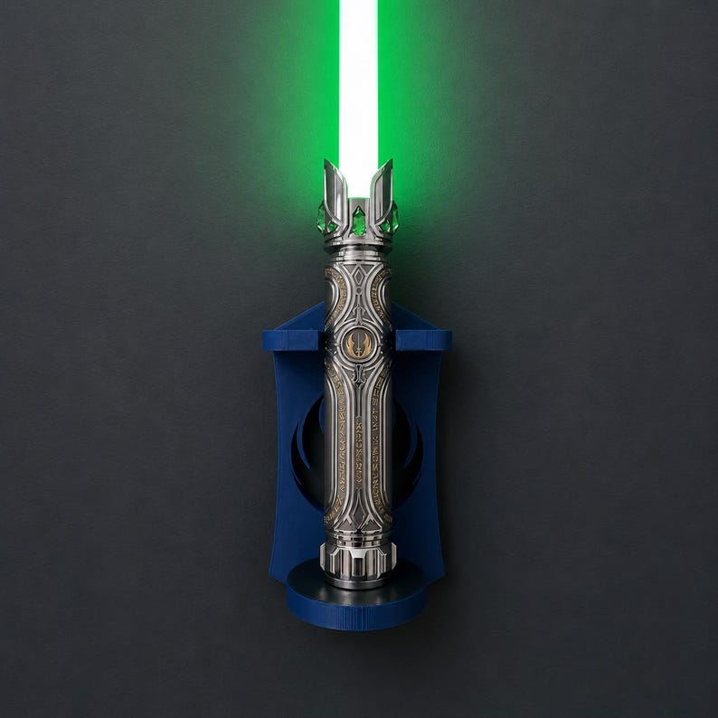 K&ouml;nnte beinhalten: Ein silberfarbener Lichtschwertgriff mit komplexen Metallgravuren und einer leuchtenden gr&uuml;nen Klinge, vertikal montiert an einer dunkelblauen Wandhalterung mit einem kreisf&ouml;rmigen Jedi-Orden-Symbol in der Mitte des Griffs.