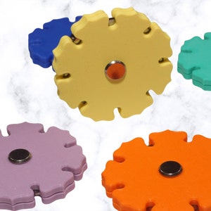 Peut inclure: Cinq jouets sensoriels en forme d'étoile de différentes couleurs : jaune, violet, orange, bleu et vert. Chaque jouet a un cercle central.