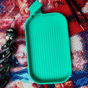 Könnte beinhalten: Ein grünes Tablett aus Kunststoff mit Rillen zum Aufbewahren von Diamant-Malwerkzeugen. Das Tablett ist flaschenförmig und hat eine quadratische Oberseite.