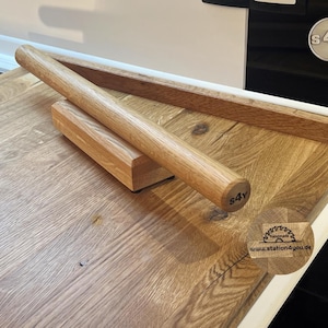 Può includere: Set di mattarello e tagliere in legno. Il mattarello è cilindrico e poggia su un blocco rettangolare. Il tagliere ha un bordo rialzato. Il mattarello ha il testo "s4y" all'estremità.