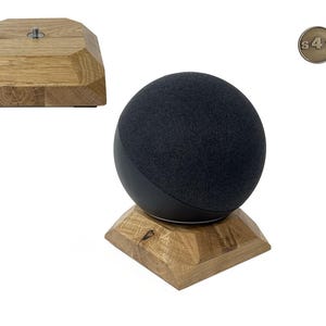 Könnte beinhalten: Ein schwarzer, kugelförmiger Smart-Lautsprecher steht auf einem Holzständer. Der Ständer besteht aus hellfarbenem Holz mit einem geometrischen Design. Ein zweiter Holzständer ist separat abgebildet. Ein kleines, rundes Metallabzeichen ist ebenfalls sichtbar.