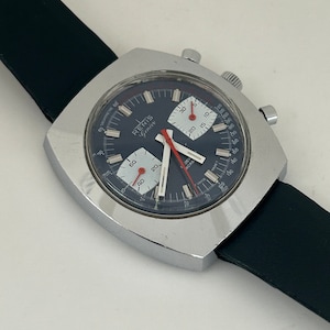 May include: A silver square-shaped chronograph wristwatch with a black face and white markings. The watch has a black leather band and the words "RENIS Gen&egrave;ve" on the face.