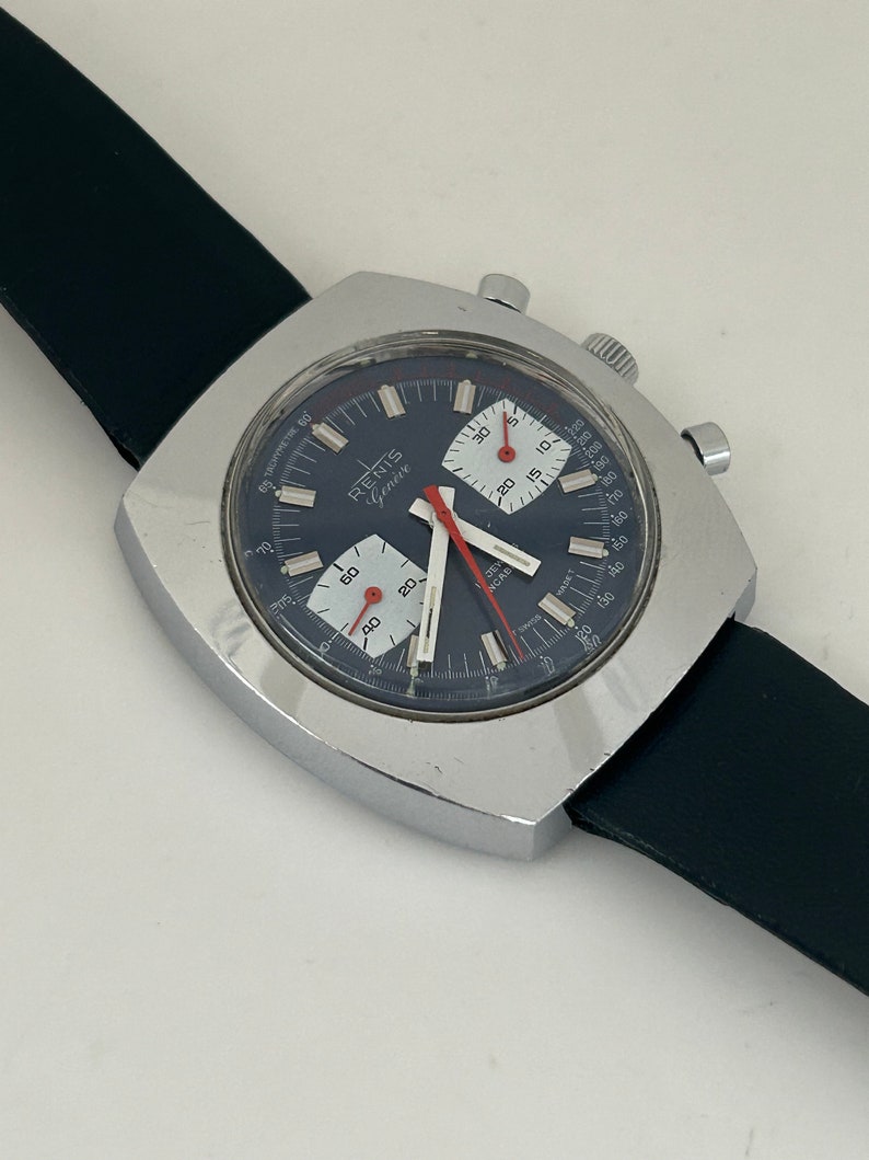 May include: A silver square-shaped chronograph wristwatch with a black face and white markings. The watch has a black leather band and the words "RENIS Gen&egrave;ve" on the face.
