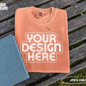May include: A peach-colored sweatshirt with the text "YOUR DESIGN HERE" in white on a wooden bench.