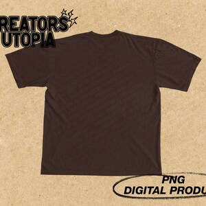 Op de afbeelding: Een bruin T-shirt met de tekst "CREATORS UTOPIA" gedrukt op de voorkant. De tekst is in zwart en wit met een stervormig ontwerp.