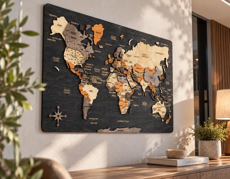 May include: A large rectangular wall-mounted world map made of layered wood pieces in shades of beige, tan, and dark gray. The continents are mounted on a dark charcoal wood background with engraved text for country names and oceans.