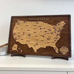 May include: A wooden map of the United States with the locations of National Hockey League teams marked. The map is on a stand and has a personalized plaque that says "The Miller Family".