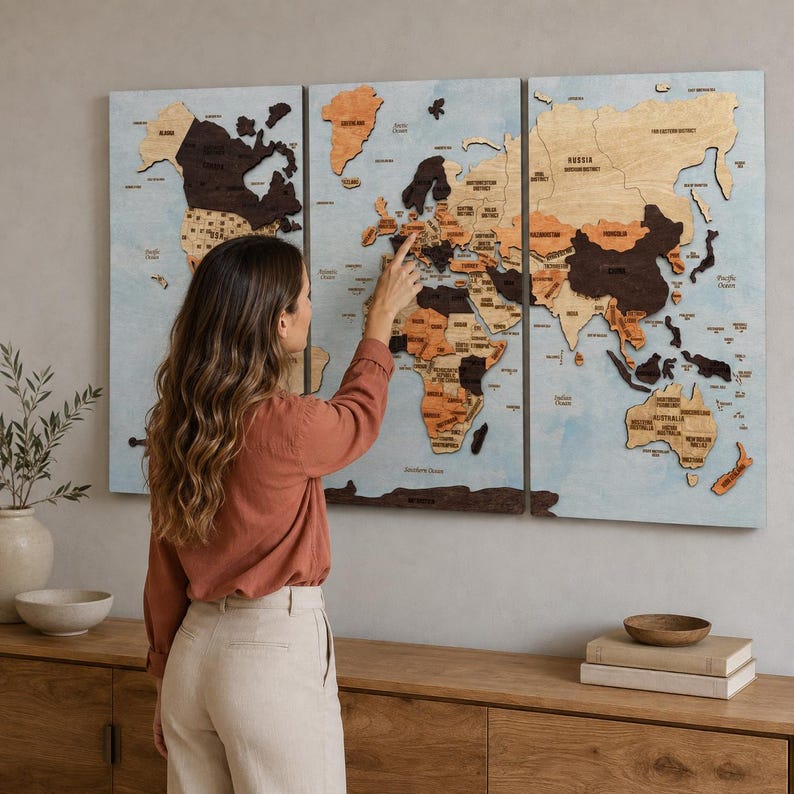 May include: A three-panel wooden world map wall art featuring continents in varying shades of brown and tan wood tones against a light blue background. The map displays country names and borders, with raised wooden pieces creating a layered effect.