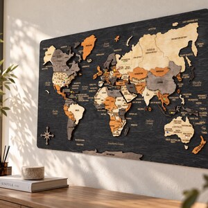 May include: A multi-layered wooden world map wall art piece featuring continents in shades of natural wood, gray, and orange, mounted on a dark, textured black wooden board with engraved country names and a compass rose icon.