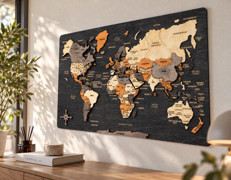 May include: A multi-layered wooden world map wall art piece featuring continents in shades of natural wood, gray, and orange, mounted on a dark, textured black wooden board with engraved country names and a compass rose icon.