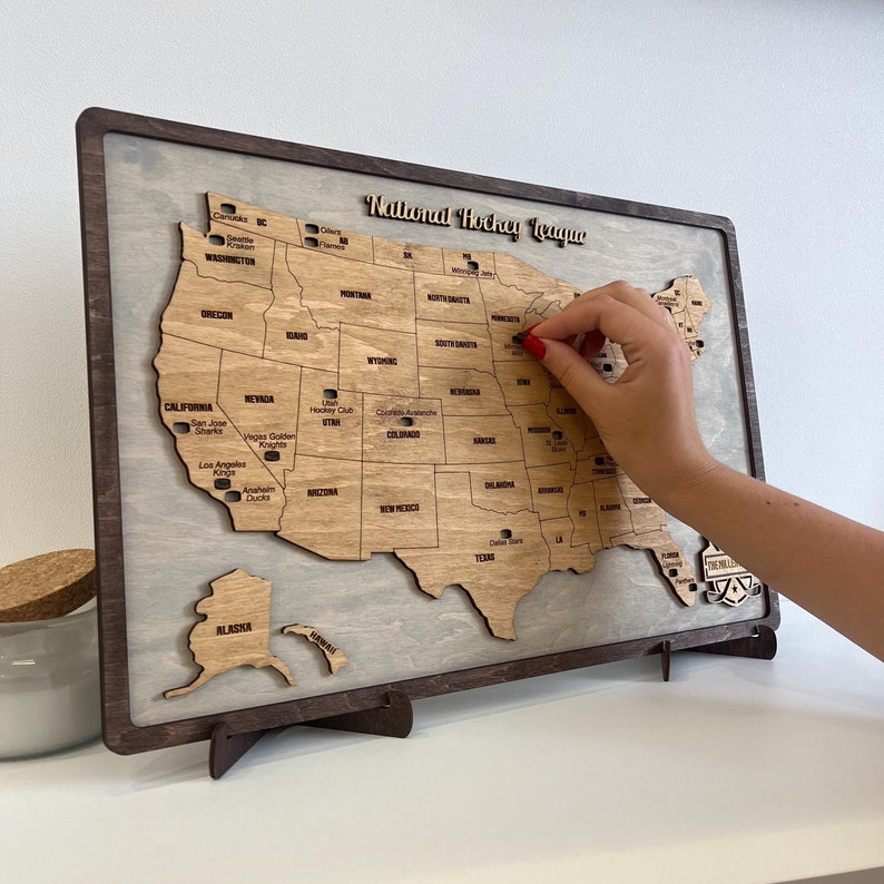 May include: A wooden map of the United States with the National Hockey League team locations marked. The map is on a stand and has a light wood finish. The map is a fun way to show your love for hockey.