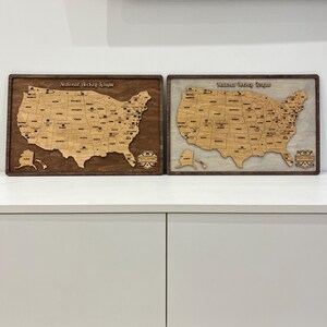May include: Two wooden maps of the United States, one with a brown background and the other with a white background. Both maps show the locations of National Hockey League and American Hockey League teams. The maps are framed in dark wood.