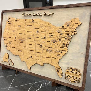 May include: A wooden map of the United States with the National Hockey League team logos in each state. The map is framed in wood and has a plaque at the bottom that says "The Miller Family".