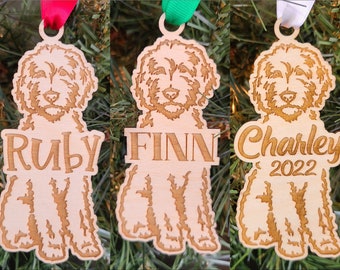 May include: Three wooden Christmas ornaments featuring a dog breed silhouette with personalized names. The ornaments are Ruby, Finn, and Charley 2022.