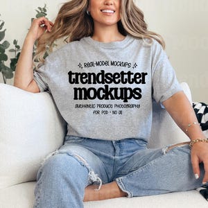 May include: A light gray t-shirt with the text "trendsetter mockups" in a bold, black font. The shirt is paired with light blue jeans. The text "REAL-MODEL MOCKUPS" and "AUTHENTIC PRODUCT PHOTOGRAPHY FOR POD - NO AI" are also visible.