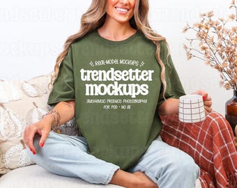 May include: An olive green t-shirt featuring white text that reads: REAL-MODEL MOCKUPS, trendsetter mockups, AUTHENTIC PRODUCT PHOTOGRAPHY, FOR POD · NO AI. The shirt has a crew neckline and short sleeves, paired with light blue denim jeans.