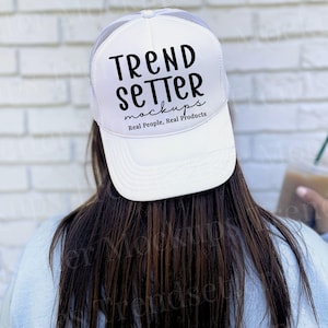 Puede incluir: Gorra de camionero blanca con el texto "TREND SETTER mockups Real People, Real Products" en escritura negra. La gorra tiene una parte trasera de malla y una visera curva. La persona sostiene una bebida con una pajita verde.