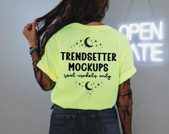 Op de afbeelding: Een neongeel t-shirt met korte mouwen en zwarte tekst op de achterkant met de tekst TRENDSETTER MOCKUPS real models only, omringd door een grafisch ontwerp van een halve maan en kleine sterren boven en onder de tekst.