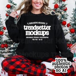 Puede incluir: Una sudadera negra con el texto "trendsetter mockups" en blanco, combinada con un pantalón de pijama a cuadros rojos y negros. La escena está ambientada con árboles de Navidad, adornos rojos y una casa de jengibre. Incluye el texto "100% authentic photos no AI".