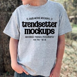 May include: A light gray t-shirt with the text "trendsetter mockups" in black, along with the phrases "real-model mockups" and "authentic product photography for POD - no AI". The shirt is being worn by a person.