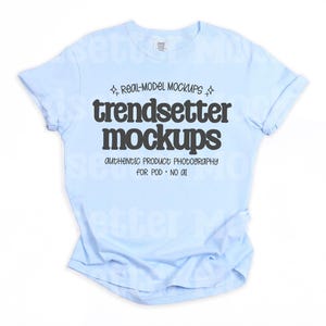 May include: A light blue t-shirt with rolled-up sleeves. The shirt features the text "trendsetter mockups" in a bold, black font, along with smaller text that reads "authentic product photography for POD • NO AI". The shirt is displayed on a white background.