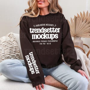 Könnte beinhalten: Ein dunkelbraunes Langarm-Sweatshirt mit weißem Text auf der Brust, der "REAL-MODEL MOCKUPS trendsetter mockups AUTHENTIC PRODUCT PHOTOGRAPHY FOR POD • NO AI" lautet, sowie "trendsetter mockups" vertikal auf dem rechten Ärmel gedruckt.
