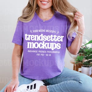 以下が含まれることがあります： 白い文字で「trendsetter mockups」と書かれた紫色のTシャツ。青いジーンズと白いスニーカーを着用しています。画像は製品モックアップです。