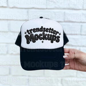 May include: A black and white trucker hat with the text "trendsetter Mockups" in a retro font. The hat has a white front panel and a black brim and mesh back. The text is in black with star accents.