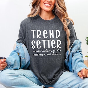 May include: A dark gray long-sleeve t-shirt with the text "TREND SETTER mockups Real People, Real Products" in white. The person is wearing a light blue denim jacket and light blue jeans.