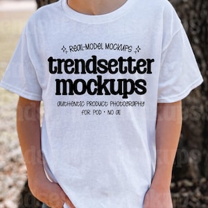 Może przedstawiać: Biała koszulka z napisem "trendsetter mockups" pogrubioną, czarną czcionką. Koszulka zawiera również tekst "REAL-MODEL MOCKUPS" i "AUTHENTIC PRODUCT PHOTOGRAPHY FOR POD • NO AI" mniejszą czcionką. Koszulka jest noszona.