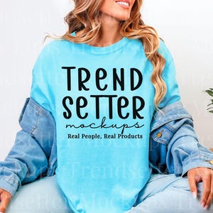 Puede incluir: Una camiseta azul claro con las palabras "TREND SETTER mockups Real People, Real Products" en negro. La persona lleva una chaqueta vaquera azul claro sobre la camiseta y unos vaqueros azules.