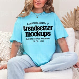 Puede incluir: Una camiseta azul claro con el texto "trendsetter mockups" en negro. La camiseta la lleva una persona sentada en un sofá blanco. También es visible el texto "AUTHENTIC PRODUCT PHOTOGRAPHY FOR POD - NO OIL".