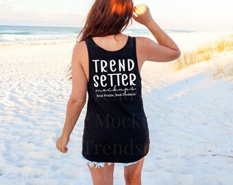 May include: A black sleeveless tank top featuring white text on the back that reads TREND SETTER mockups Real People, Real Products. The garment has a scoop neckline and a racerback style, shown from the back view.