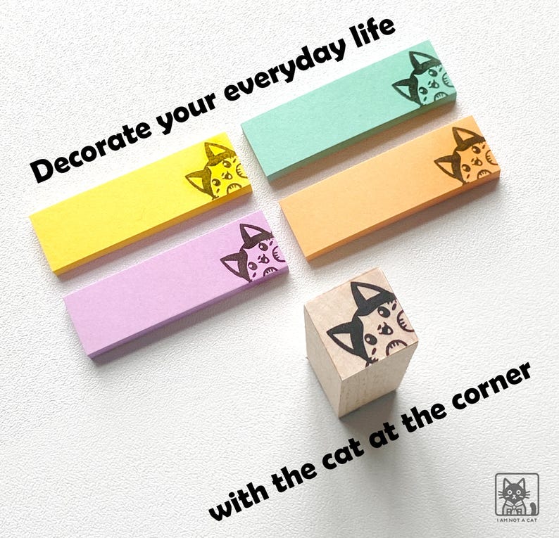 May include: A collection of colorful sticky notes and a wooden stamp featuring a cat design. The sticky notes are in yellow, pink, orange, and teal. Text on the image reads "Decorate your everyday life with the cat at the corner."