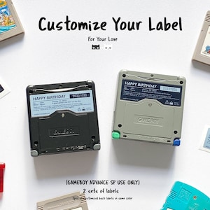 Könnte beinhalten: Zwei Game Boy Advance SP-Spielpatronen mit benutzerdefinierten Etiketten. Die Etiketten sind schwarz und grau mit dem Text "HAPPY BIRTHDAY" und dem Datum "20231023". Der Text "GAMEBOY ADVANCE SP USE ONLY" und "2 sets of labels" ist unter den Patronen gedruckt.