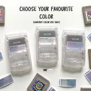 May include: Three clear plastic Game Boy Color cases with the text "GAMECAT COLOR" printed on the front. The cases are arranged in a row on a white surface.