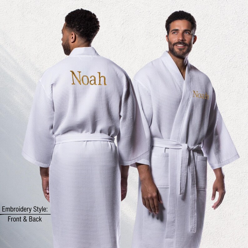 May include: White waffle-weave robe with the name "Noah" embroidered in gold thread on the back and front. The robe has a shawl collar, a waist tie, and pockets. The image shows the front and back of the robe.