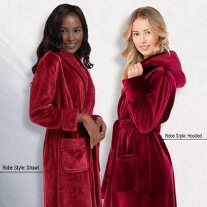 May include: Two women wearing red robes. One robe has a shawl collar, the other has a hood. Both robes have pockets and a belt. The robes are made of a soft, plush material.