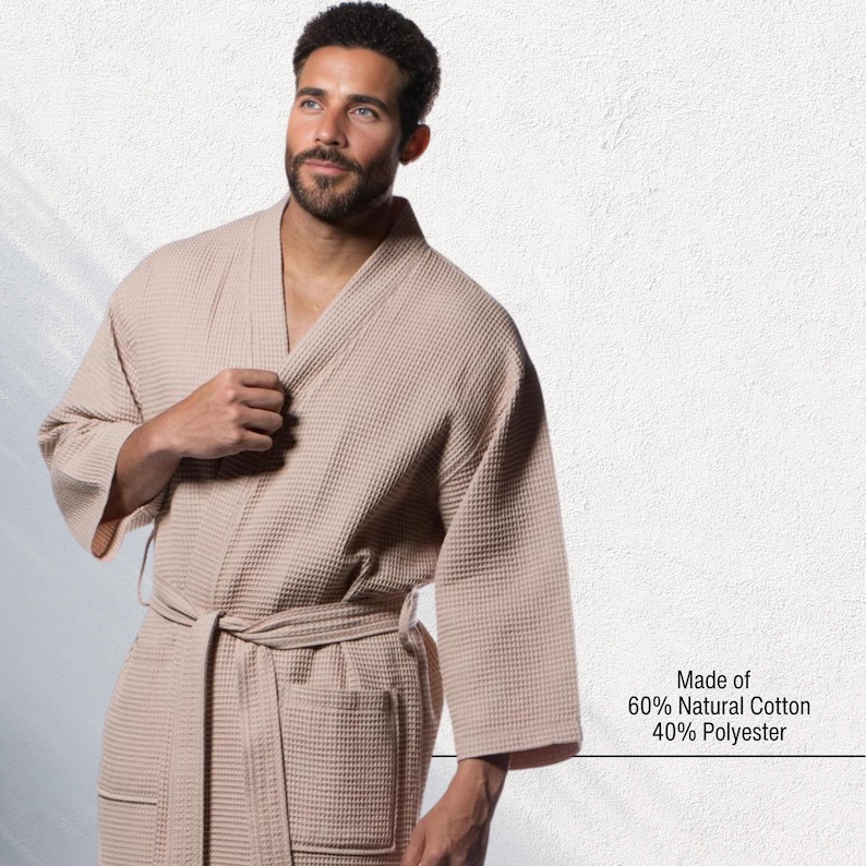 May include: A beige waffle-weave robe with a matching belt and pockets. The robe is made of 60% natural cotton and 40% polyester. The model is wearing the robe. The robe is a comfortable and stylish garment for lounging.
