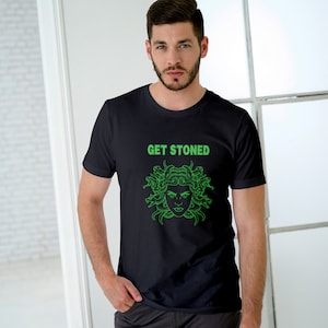 Könnte beinhalten: Ein schwarzes T-Shirt mit einem grünen Motiv einer Medusa-Kopf mit Schlangen als Haaren. Der Text "GET STONED" befindet sich über dem Motiv.