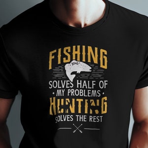 Op de afbeelding: Zwart T-shirt met een gele afbeelding waarop staat "Vissen lost de helft van mijn problemen op. Jagen lost de rest op." met een visillustratie.