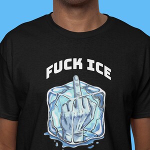 May include: Black t-shirt with the text "FUCK ICE" in white block letters above a graphic of a hand giving the middle finger, encased in a block of ice. The hand and ice are shades of blue.