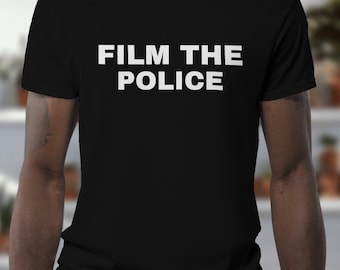 Peut inclure: T-shirt noir avec le texte "FILM THE POLICE" en lettres blanches.