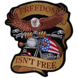 May include: A black and brown embroidered patch with a bald eagle perched on a motorcycle. The eagle is holding the handlebars and has its wings spread. The motorcycle has an American flag on the gas tank. The patch has a banner that reads "Freedom Isn't Free".