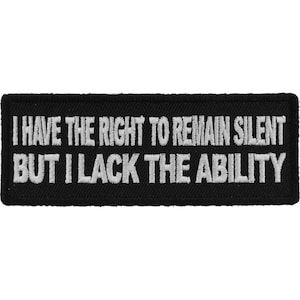 以下が含まれることがあります： 黒い刺繍パッチに白い文字で「沈黙する権利はあるが、能力がない。」と書いてある