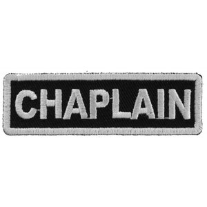 May include: A black and white embroidered patch with the word "CHAPLAIN" in white lettering.