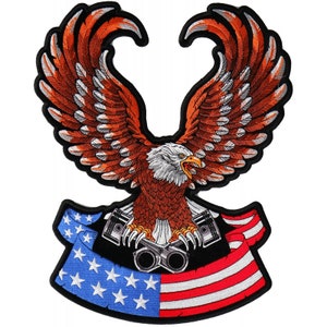 May include: An embroidered patch featuring a bald eagle with outstretched wings holding two pistons in its talons. The eagle is perched on top of a red, white, and blue American flag.