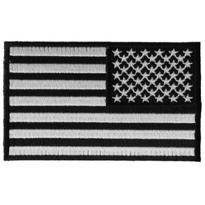 Puede incluir: Parche bordado de la bandera estadounidense en blanco y negro. Las estrellas y las rayas son blancas sobre un fondo negro.