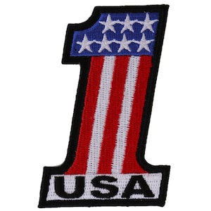 May include: An embroidered patch in the shape of the number one with the American flag design. The patch has red and white stripes and blue stars in the top left corner. The word "USA" is written in black letters at the bottom of the patch.