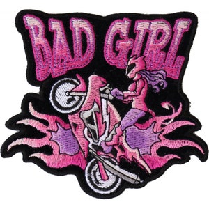 Peut inclure: Écusson brodé avec les mots "BAD GIRL" en rose, au-dessus d'une moto rose avec un pilote. La moto est entourée de flammes roses et violettes, le tout sur un fond noir.